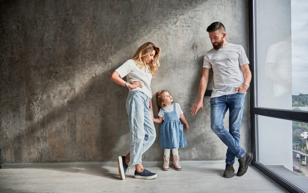 Happy family standing by the wall in new apartment.